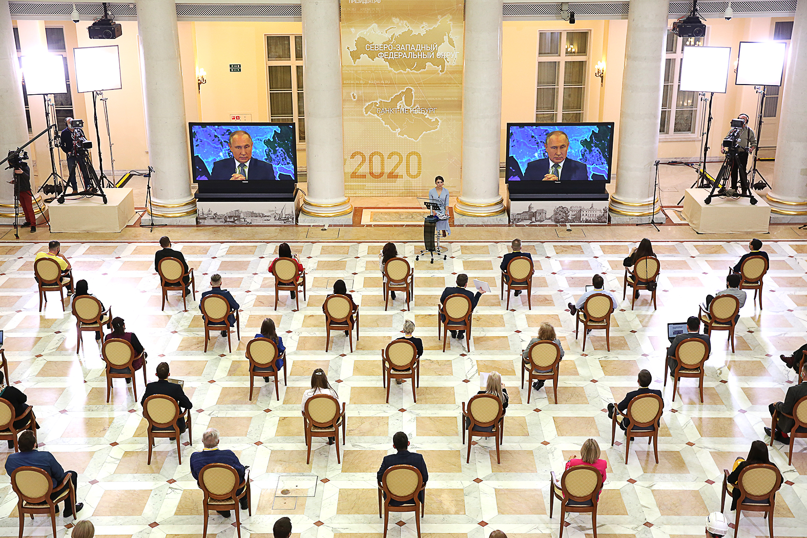 Újságírók ülnek a szentpétervári Borisz Jelcin könyvtár dísztermében Vlagyimir Putyin orosz elnök szokásos évvégi sajtótájékoztatóján, amit a koronavírus miatt videókonferencia formájában, kivetítőkön követnek #moszkvater